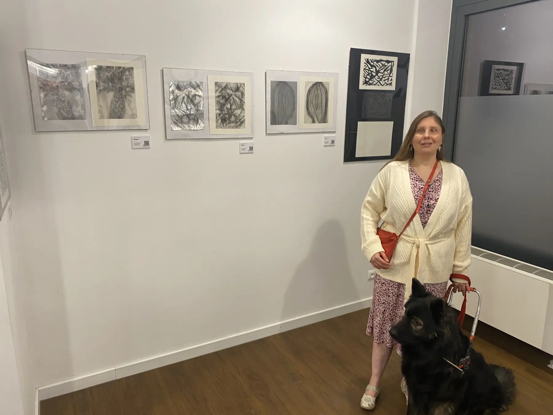 Magdalena Rutkowska i Pinot stoją w jasnej sali wystawowej. Po prawej, na wysokim czarnym podkładzie, pokazano trzy stany „Walki”: u góry czarno-białą odbitkę z farbą, pośrodku ciemną metalową matrycę, a na dole jasny relief bez farby. Na ścianie obok wiszą oprawione grafiki innych osób.