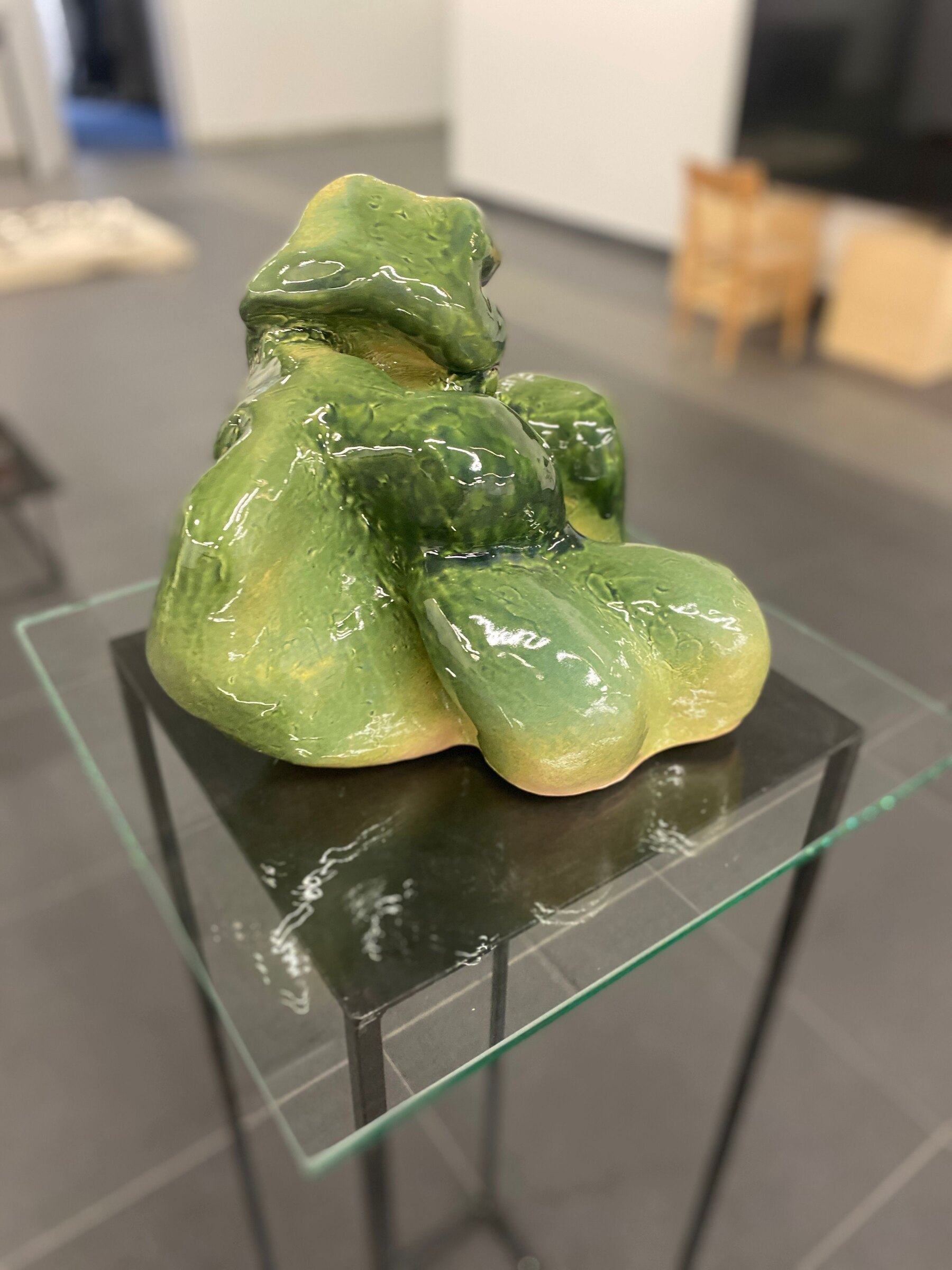 Pionowe ujęcie zielonej rzeźby ceramicznej od strony przeciwnej. Dolną połowę tworzą trzy szerokie, obłe wypukłości; nad nimi spiętrzają się mniejsze formy, zwieńczone spłaszczoną fałdą.