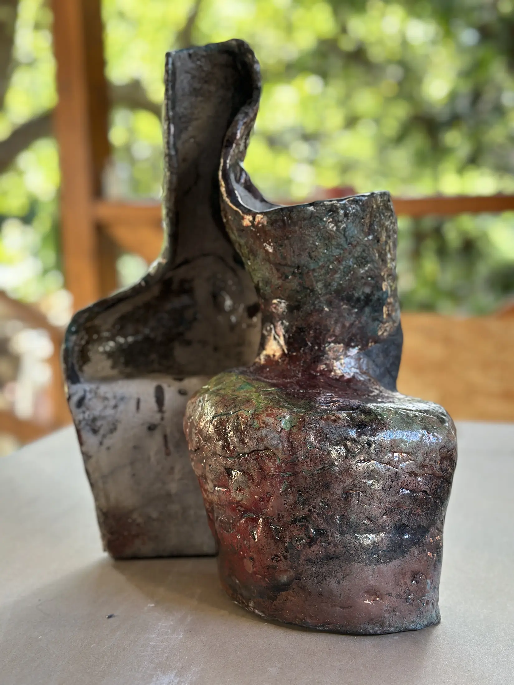 Naczyniopodobna rzeźba ceramiczna widziana od strony dwóch obłych części przy podstawie. Prawa, wysunięta ku przodowi partia jest czerwono-miedziana, miejscami zielonkawa i silnie połyskliwa; z lewej wznosi się ciemniejsza ściana o nieregularnej krawędzi. Pomiędzy wysokimi częściami biegnie otwarte zagłębienie. Powierzchnia jest nierówna, spękana, pokryta czernią, grafitem, czerwienią, miedzią i drobnymi turkusowymi polami.